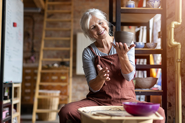 Mature woman crafting a clay pot in her studio.
